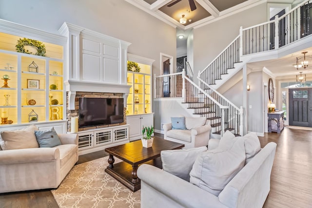 living room featuring coffered ceiling, stairs, crown molding, a high ceiling, and wood finished floors