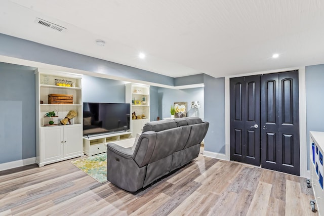 living area with baseboards, visible vents, and light wood-style floors