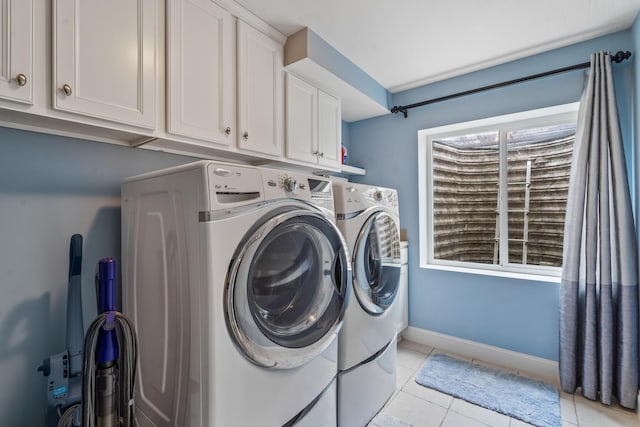 laundry room featuring light tile patterned flooring, baseboards, washer and dryer, and cabinet space