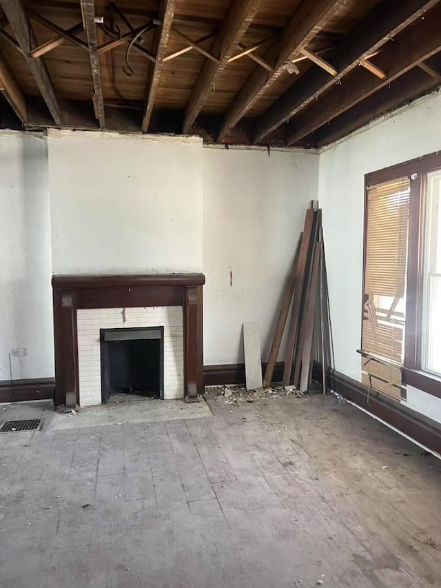 unfurnished living room featuring a tile fireplace, visible vents, and hardwood / wood-style flooring