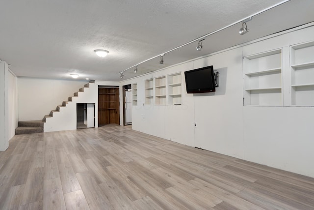 2520 Saltergate Dr, Dublin, OH 43016 - unfurnished living room featuring stairs, a textured ceiling, light wood-style flooring, track lighting, and built in features