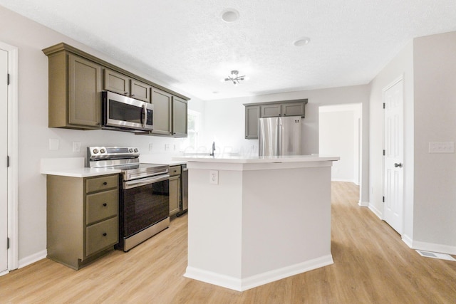 632 Tall Oaks Dr, Gahanna, OH 43230 - kitchen with light wood-style floors, a center island, light countertops, a textured ceiling, and stainless steel appliances