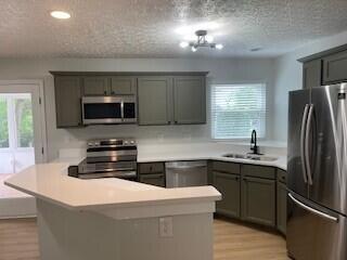 632 Tall Oaks Dr, Gahanna, OH 43230 - kitchen featuring stainless steel appliances, a sink, light wood finished floors, light countertops, and a textured ceiling