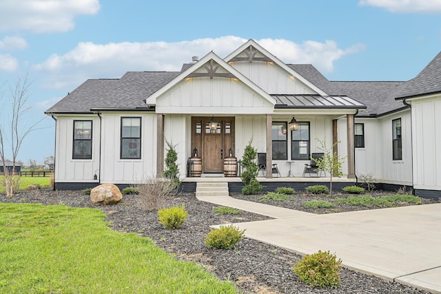 modern farmhouse style home with roof with shingles, board and batten siding, a porch, and a front yard