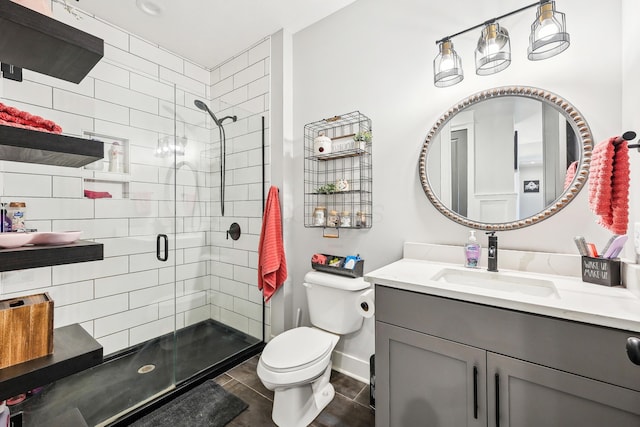 bathroom with tile patterned flooring, a stall shower, vanity, baseboards, and toilet