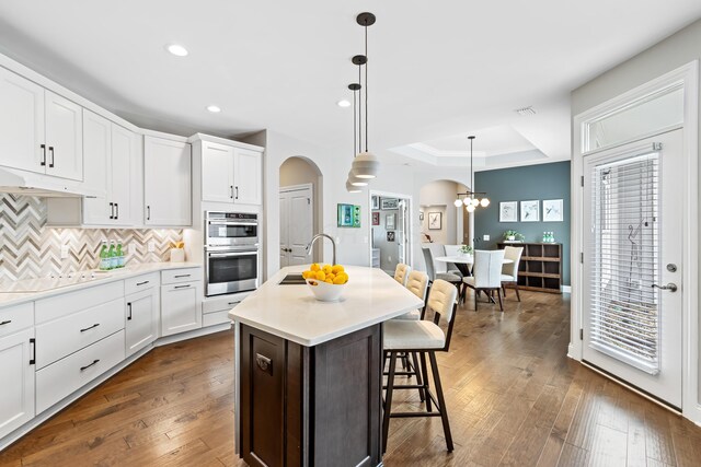 3325 Strickland Dr, New Albany, OH 43054 - kitchen featuring stainless steel double oven, under cabinet range hood, electric stovetop, a sink, and arched walkways