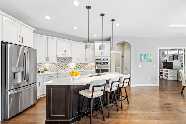 3325 Strickland Dr, New Albany, OH 43054 - kitchen with stainless steel appliances, arched walkways, backsplash, white cabinetry, and light countertops