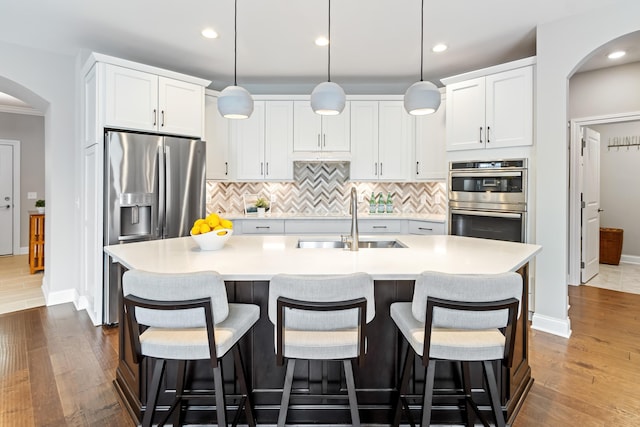 3325 Strickland Dr, New Albany, OH 43054 - kitchen featuring dark wood finished floors, stainless steel appliances, backsplash, a sink, and arched walkways