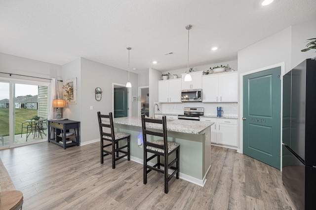 458 Madison Way, Plain City, OH 43064 - kitchen with stainless steel appliances, a breakfast bar, decorative backsplash, an island with sink, and light wood-style flooring