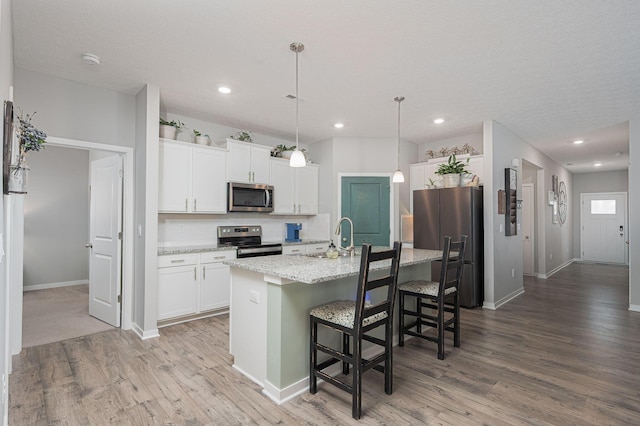 458 Madison Way, Plain City, OH 43064 - kitchen with a kitchen island with sink, a kitchen bar, appliances with stainless steel finishes, white cabinetry, and light wood-type flooring
