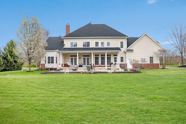 back of property with french doors, a patio, a lawn, and a chimney