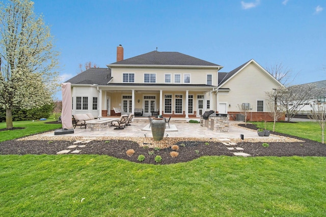 back of house with french doors, a patio, a lawn, and an outdoor kitchen
