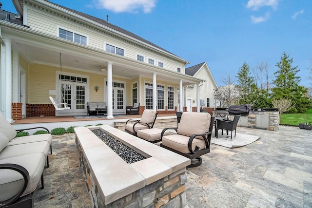 view of patio / terrace with french doors, an outdoor kitchen, and an outdoor fire pit