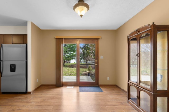 entryway with french doors, baseboards, light wood finished floors, and visible vents