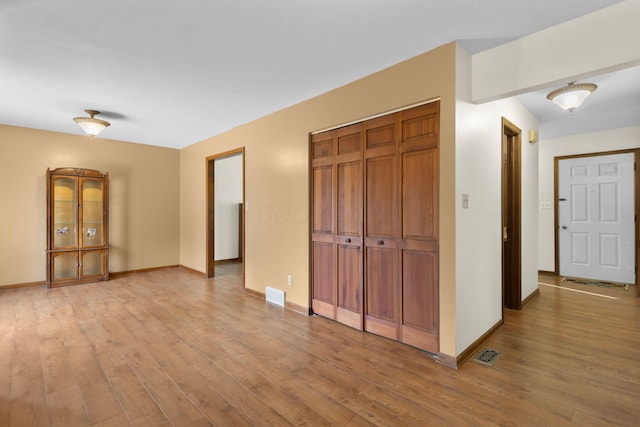 interior space with a closet, baseboards, light wood finished floors, and visible vents