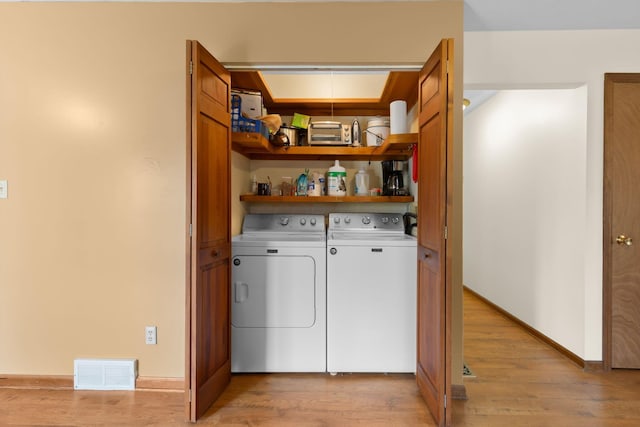 laundry room with light wood-type flooring, laundry area, separate washer and dryer, and visible vents