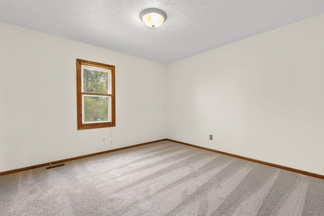 carpeted empty room featuring a textured ceiling, baseboards, and visible vents