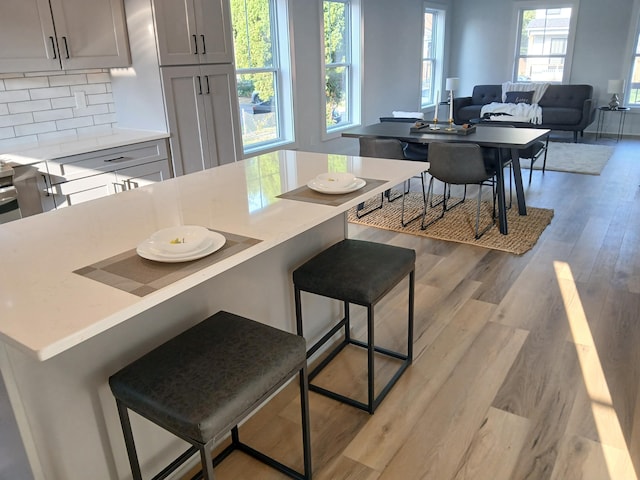 166 Miami Ave, Columbus, OH 43203 - kitchen featuring a breakfast bar, light countertops, gray cabinetry, and light wood-style flooring