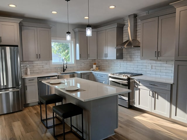 166 Miami Ave, Columbus, OH 43203 - kitchen featuring stainless steel appliances, wall chimney exhaust hood, gray cabinetry, wood finished floors, and recessed lighting