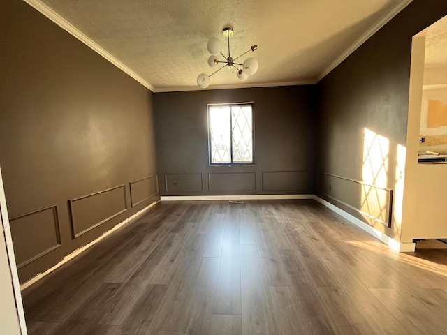 unfurnished room featuring crown molding, dark wood-style floors, a decorative wall, a notable chandelier, and wainscoting