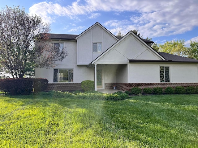 traditional-style home with stucco siding, a front lawn, and brick siding