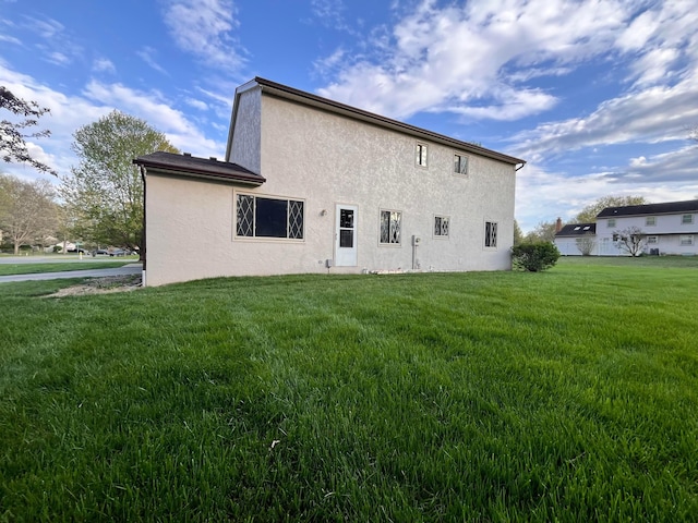 back of property featuring stucco siding and a lawn