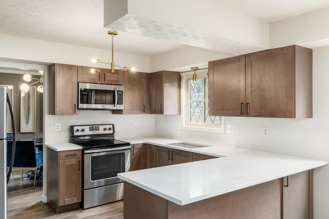 11795 Huntington Way NW, Pickerington, OH 43147 - kitchen with appliances with stainless steel finishes, light wood-type flooring, a peninsula, and light countertops