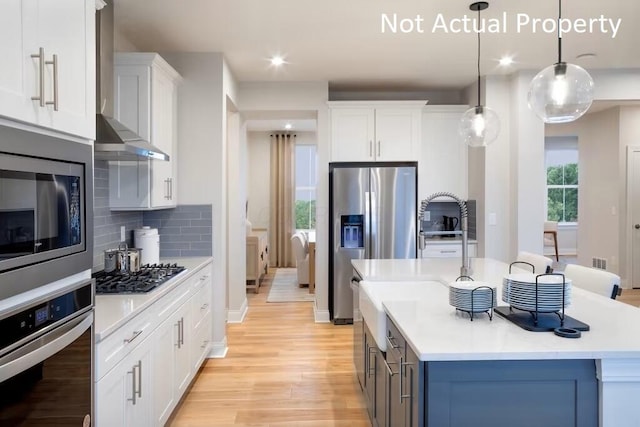 kitchen with tasteful backsplash, stainless steel appliances, light wood finished floors, light countertops, and a kitchen island