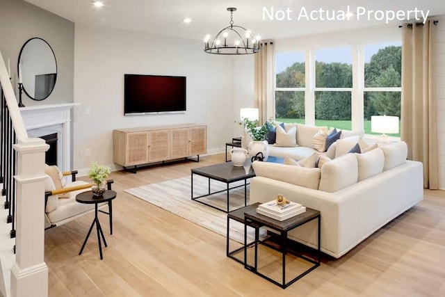 living area featuring light wood-style floors, an inviting chandelier, a fireplace, baseboards, and recessed lighting
