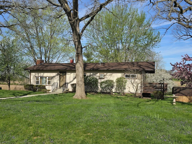 view of front of property with entry steps, a wooden deck, a front lawn, and a chimney