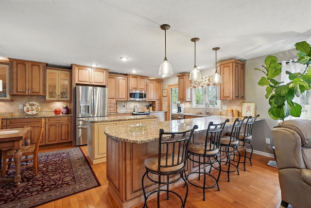 397 E Schrock Rd, Westerville, OH 43081 - kitchen with a peninsula, light wood finished floors, appliances with stainless steel finishes, light stone counters, and a center island