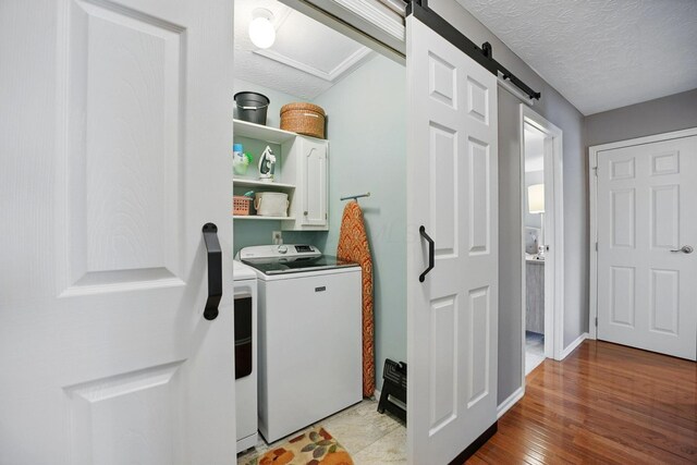 397 E Schrock Rd, Westerville, OH 43081 - clothes washing area with separate washer and dryer, a textured ceiling, a barn door, light wood finished floors, and cabinet space