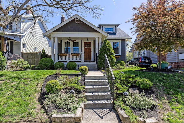 view of front of property with a ceiling fan, a porch, a front lawn, and fence
