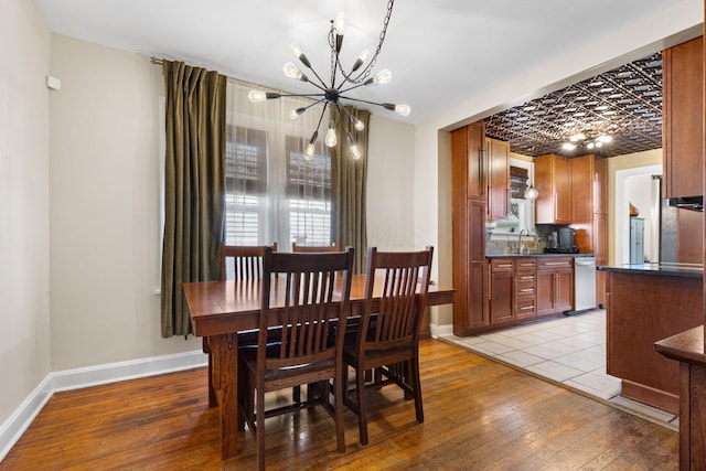 dining area featuring a chandelier, light wood-style flooring, and baseboards