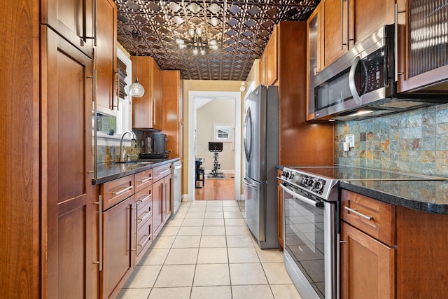 kitchen featuring glass insert cabinets, a sink, backsplash, brown cabinets, and appliances with stainless steel finishes