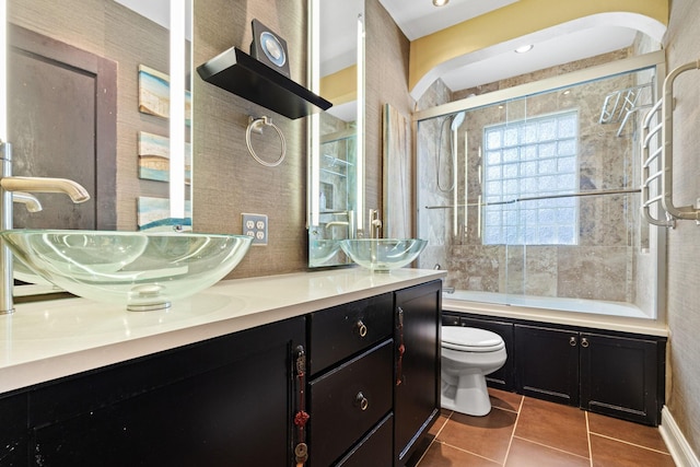 full bathroom featuring tile patterned floors, toilet, enclosed tub / shower combo, and a sink