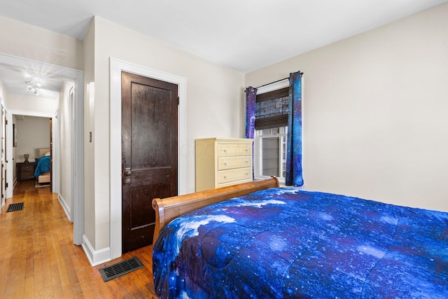 bedroom featuring wood-type flooring, baseboards, and visible vents
