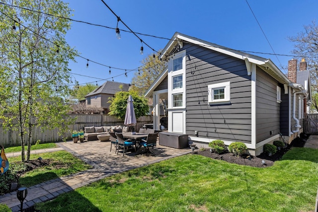 rear view of house featuring outdoor lounge area, a chimney, a lawn, a fenced backyard, and a patio area