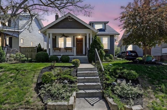 bungalow featuring a yard, a porch, a chimney, and fence