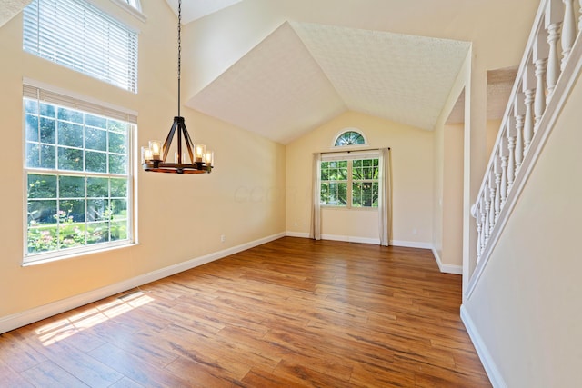 488 Springwood Lake Dr, Columbus, OH 43230 - unfurnished living room with hardwood / wood-style flooring, a chandelier, stairs, baseboards, and lofted ceiling