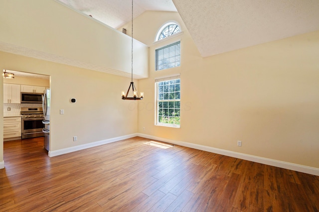 488 Springwood Lake Dr, Columbus, OH 43230 - unfurnished room featuring a chandelier, baseboards, high vaulted ceiling, and wood finished floors