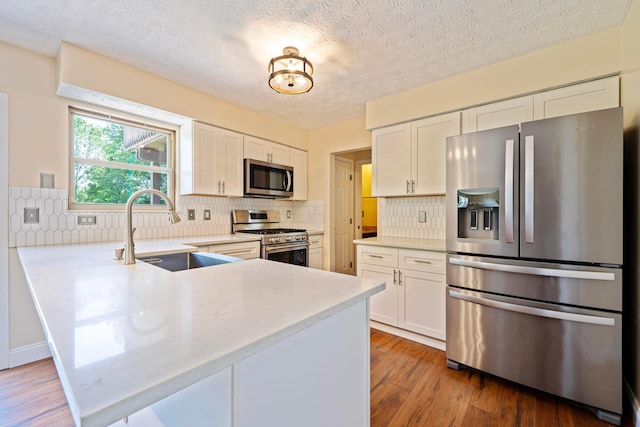 488 Springwood Lake Dr, Columbus, OH 43230 - kitchen with stainless steel appliances, a sink, a peninsula, white cabinets, and a textured ceiling