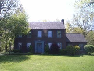 colonial house featuring a chimney and a front yard