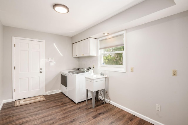 clothes washing area featuring visible vents, baseboards, dark wood-type flooring, independent washer and dryer, and cabinet space