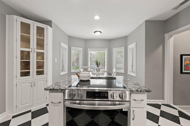 kitchen with visible vents, stone counters, dark floors, and stainless steel electric range oven
