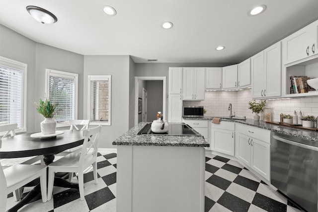 kitchen with a kitchen island, black electric cooktop, a sink, dishwasher, and light floors