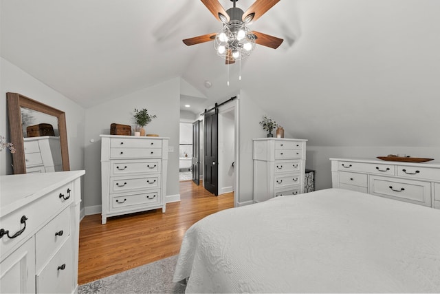 bedroom featuring a barn door, light wood-style floors, a ceiling fan, baseboards, and lofted ceiling