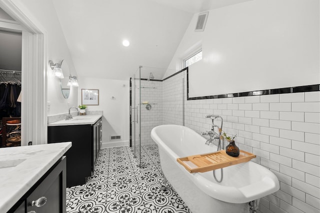 bathroom featuring visible vents, a freestanding bath, tile walls, a stall shower, and a sink