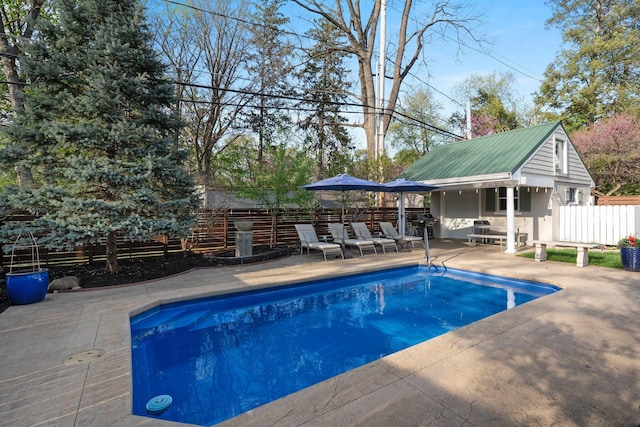 view of swimming pool featuring fence, a fenced in pool, an outbuilding, and a patio area