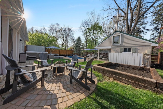 view of patio / terrace with a fenced backyard, an outbuilding, a jacuzzi, and an outdoor fire pit